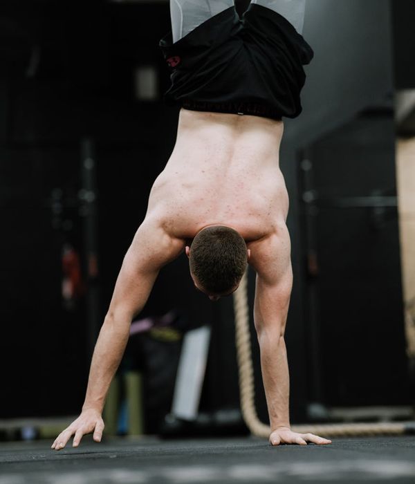 Athletic man performing core stabilization exercises in a dark gym.
